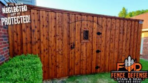 A dark stained wood fence with a decorative gate next to a brick house by Fence Defense in Plano, TX