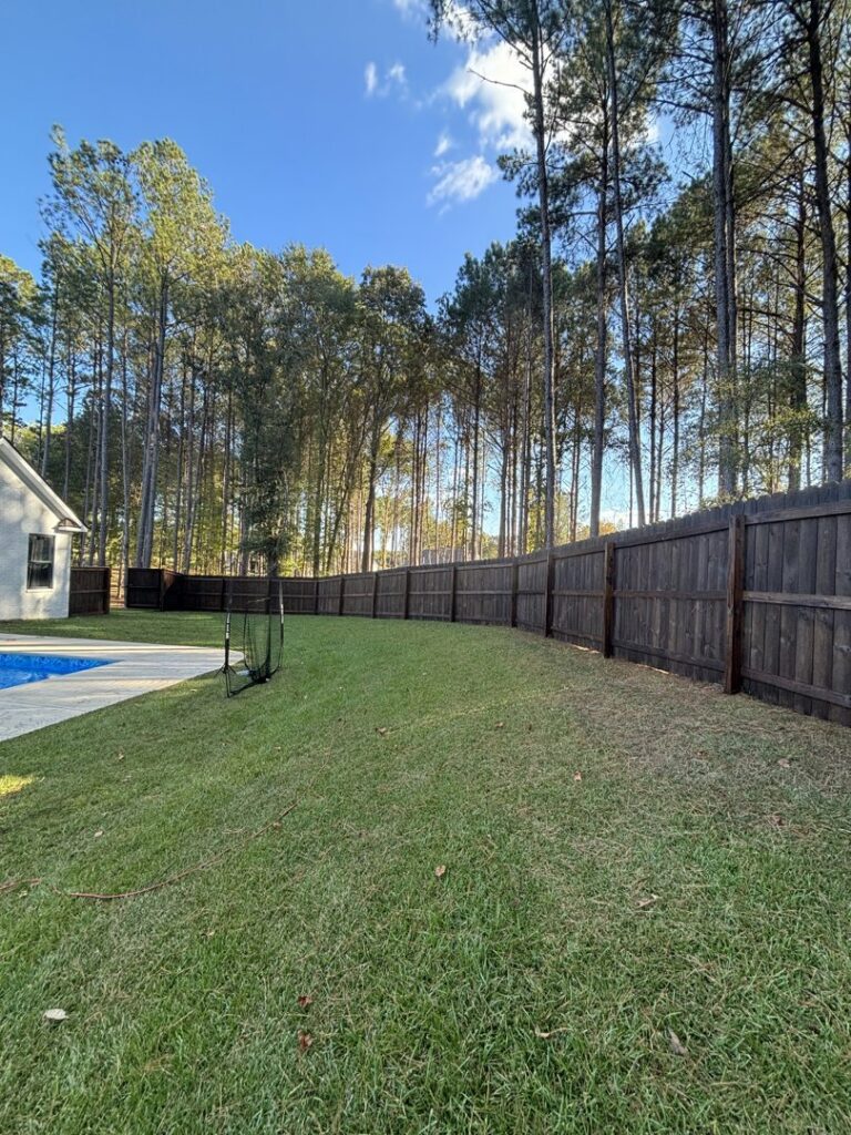 A dark stained wood privacy fence installed around a backyard pool by TC Fencing LLC in Tuscaloosa, AL.