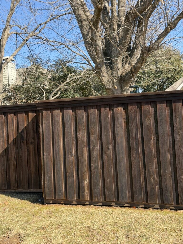 A newly installed dark stained wood privacy fence in a residential setting by Dallas Fence in Dallas, TX.