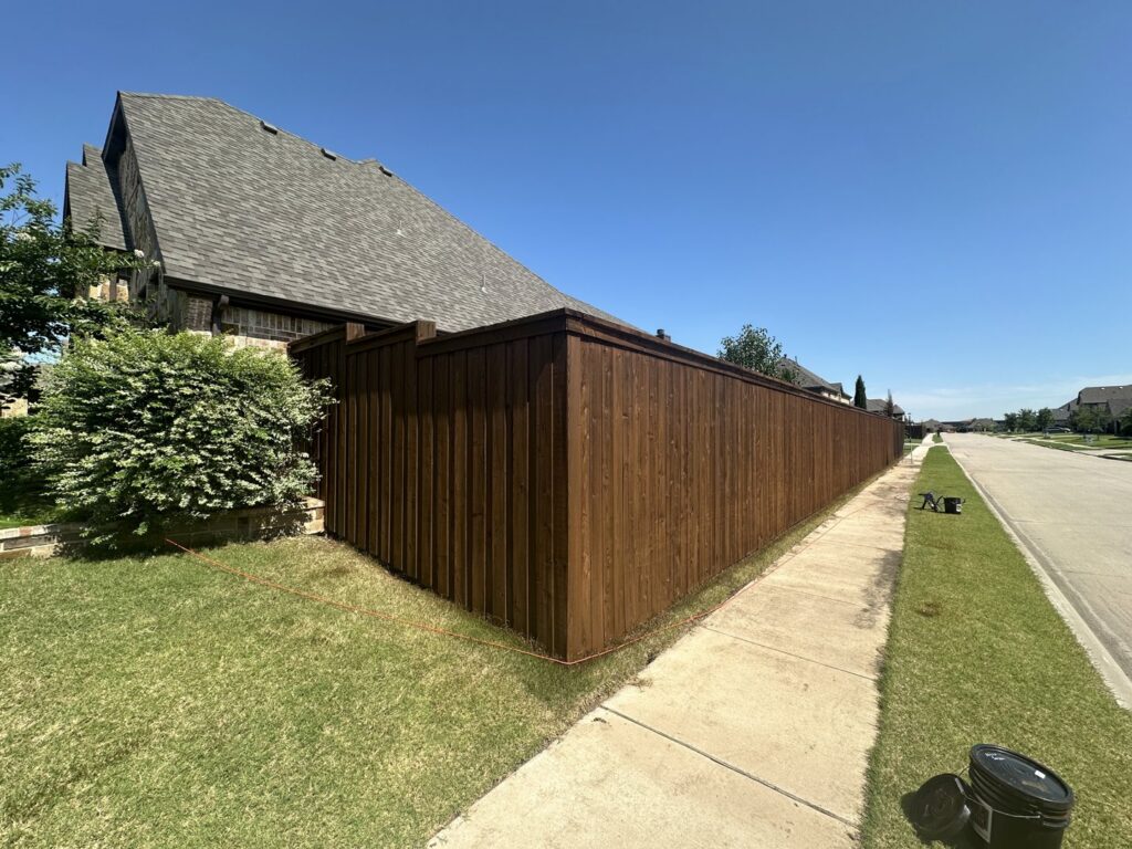 A long, dark-stained wood privacy fence installed along a residential property and sidewalk by NTX-Exterior Services in Dallas, TX.