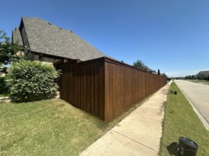 A long, dark-stained wood privacy fence installed along a residential property and sidewalk by NTX-Exterior Services in Dallas, TX.