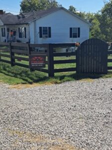 A dark-stained wooden fence with wire mesh and a matching gate installed by Stapleton Fencing LLC in Lexington, KY.