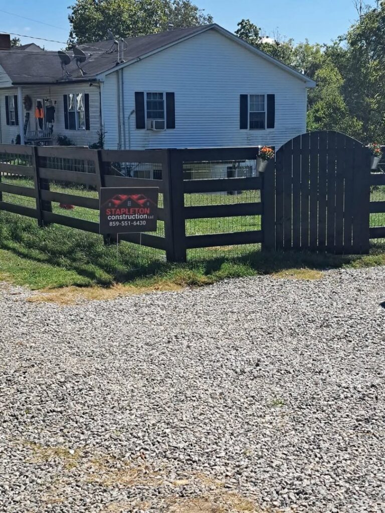 A dark-stained wooden fence with wire mesh and a matching gate installed by Stapleton Fencing LLC in Lexington, KY.