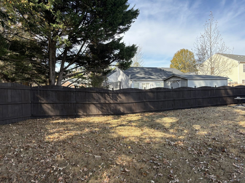 A newly installed or stained dark wooden fence in a residential backyard by Myers & Dunlap Fence Repair in Greenville, SC.