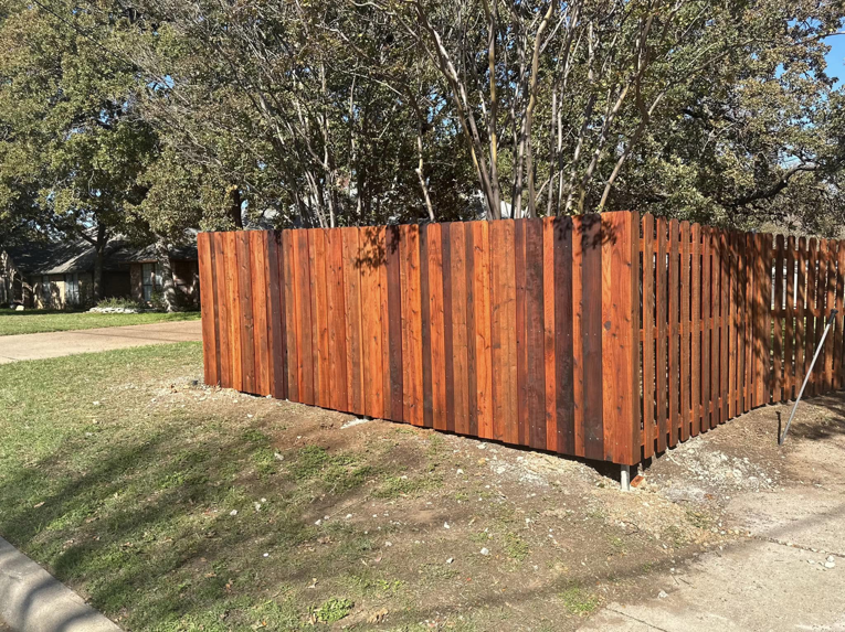 A newly installed dark-stained wooden privacy fence at a property corner by Stevenson Brothers Fencing in Fort Worth, TX