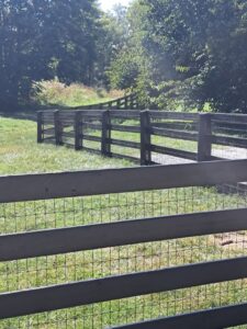 A dark-stained wooden fence with wire mesh installed in a grassy area by Stapleton Fencing LLC in Lexington, KY.