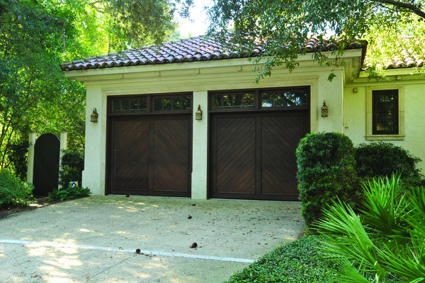 Dark wood garage doors with diagonal patterns and windows on a stucco home by Overhead Door Company of the Great Plains in Lawton, OK.