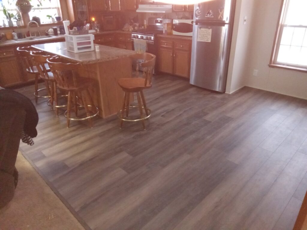 A kitchen featuring newly installed dark wood-look flooring by Carpet Warehouse in Lafayette, IN.