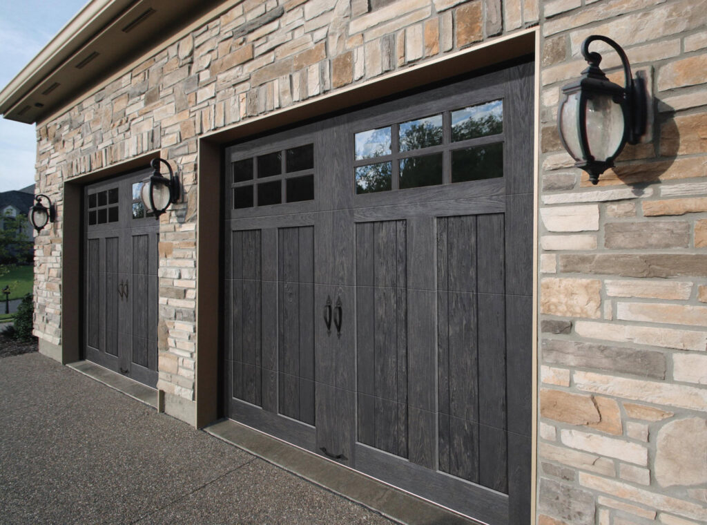 Two dark wood-look garage doors installed on a stone house by Access Garage Doors-Chattanooga, TN