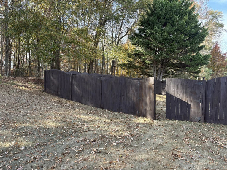 A dark-stained wooden fence with an open gate, indicating a recent installation by Myers & Dunlap Fence Repair in Greenville, SC.