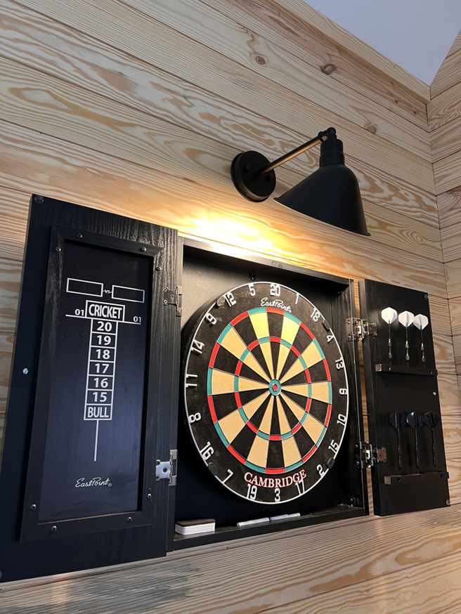 A wall sconce providing illumination for a dartboard area, installed by Ampler Electrical Services in Wilmington, NC.