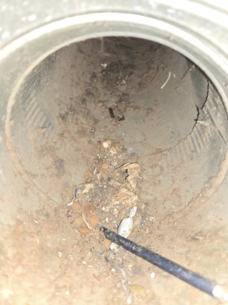 A debris-filled HVAC duct interior with a cleaning tool visible, demonstrating work by Aero Brush Duct Cleaning in Billings, MT.