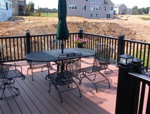 A finished deck with black railings and outdoor furniture, overlooking a new construction area, by Chesley Fence & Deck in Fairview Heights, IL.