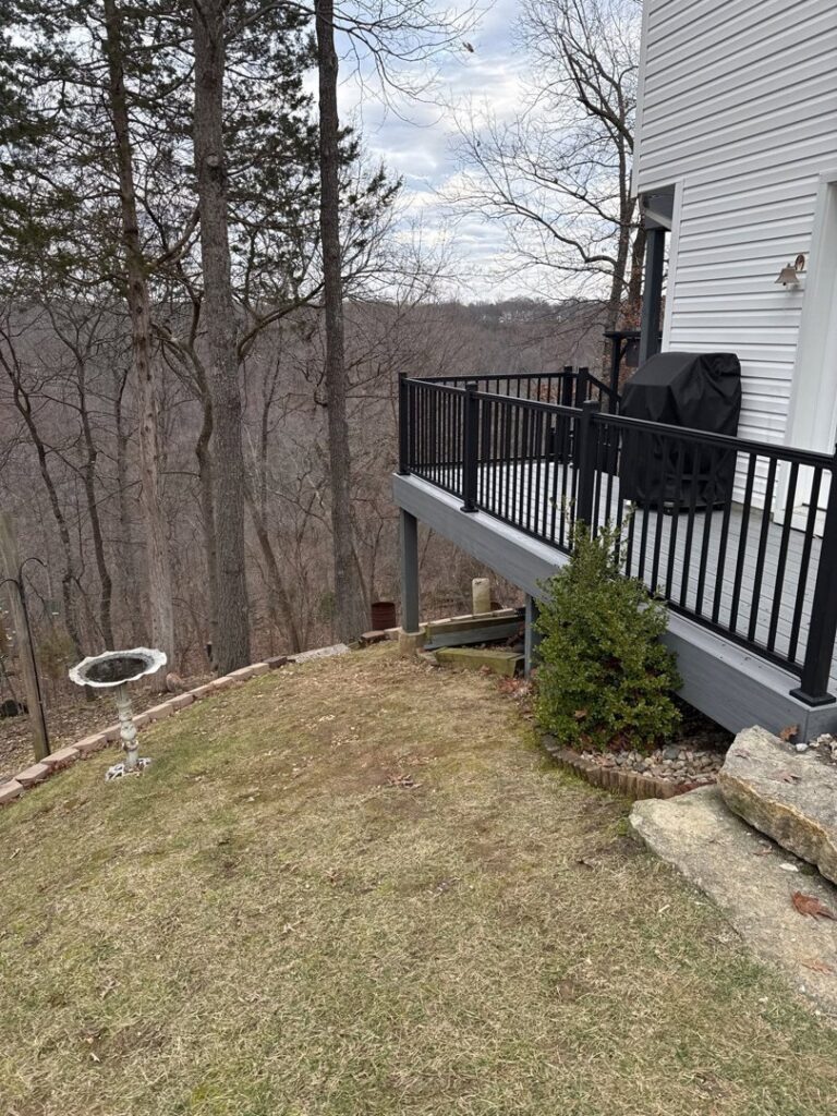 A modern deck with black railings offering a scenic view of a wooded area, built by Chesley Fence & Deck in Fairview Heights, IL.