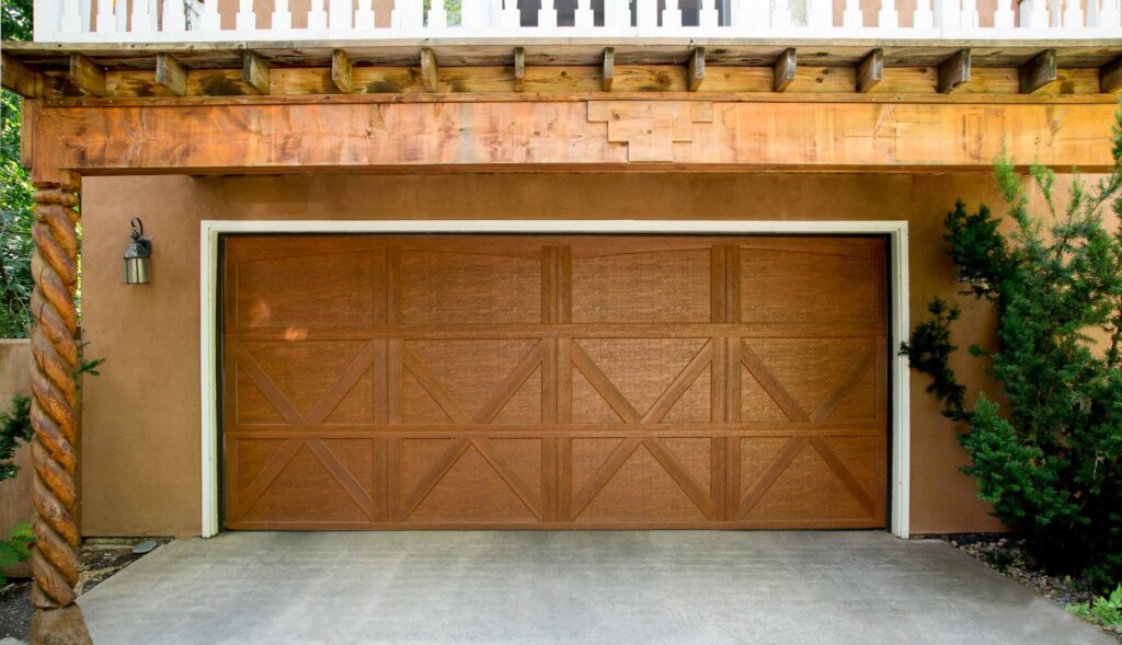 A decorative brown garage door installed on a stucco home by Overhead Door Company of Salem in Salem, OR.