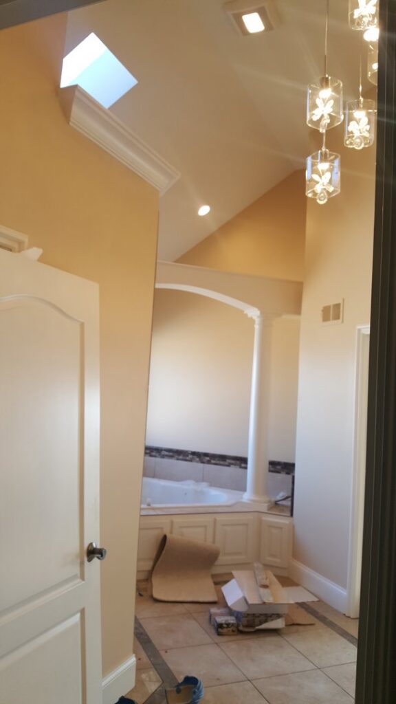 A decorative chandelier and recessed lighting installed in a hallway leading to a bathroom by Fiedler Electric in Higginsville, MO.