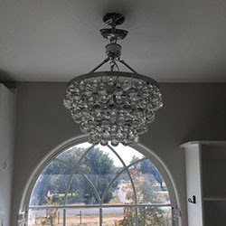 A decorative crystal chandelier light fixture, ready for or recently installed by Molitor Electric in Austin, TX.