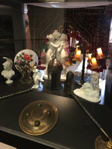 A display of decorative items with a large Persian rug hanging in the background at Art Of Persia in Portland, OR.