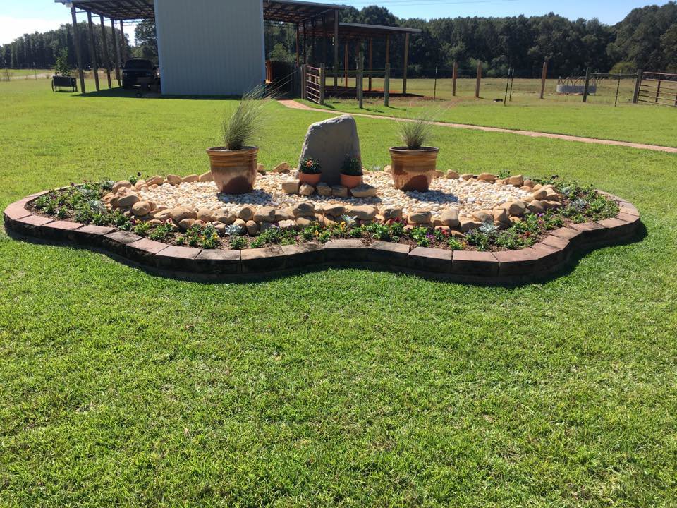 A decorative garden bed with rocks, plants, and edging installed by L&L Lawn Care Service in Dothan, AL.