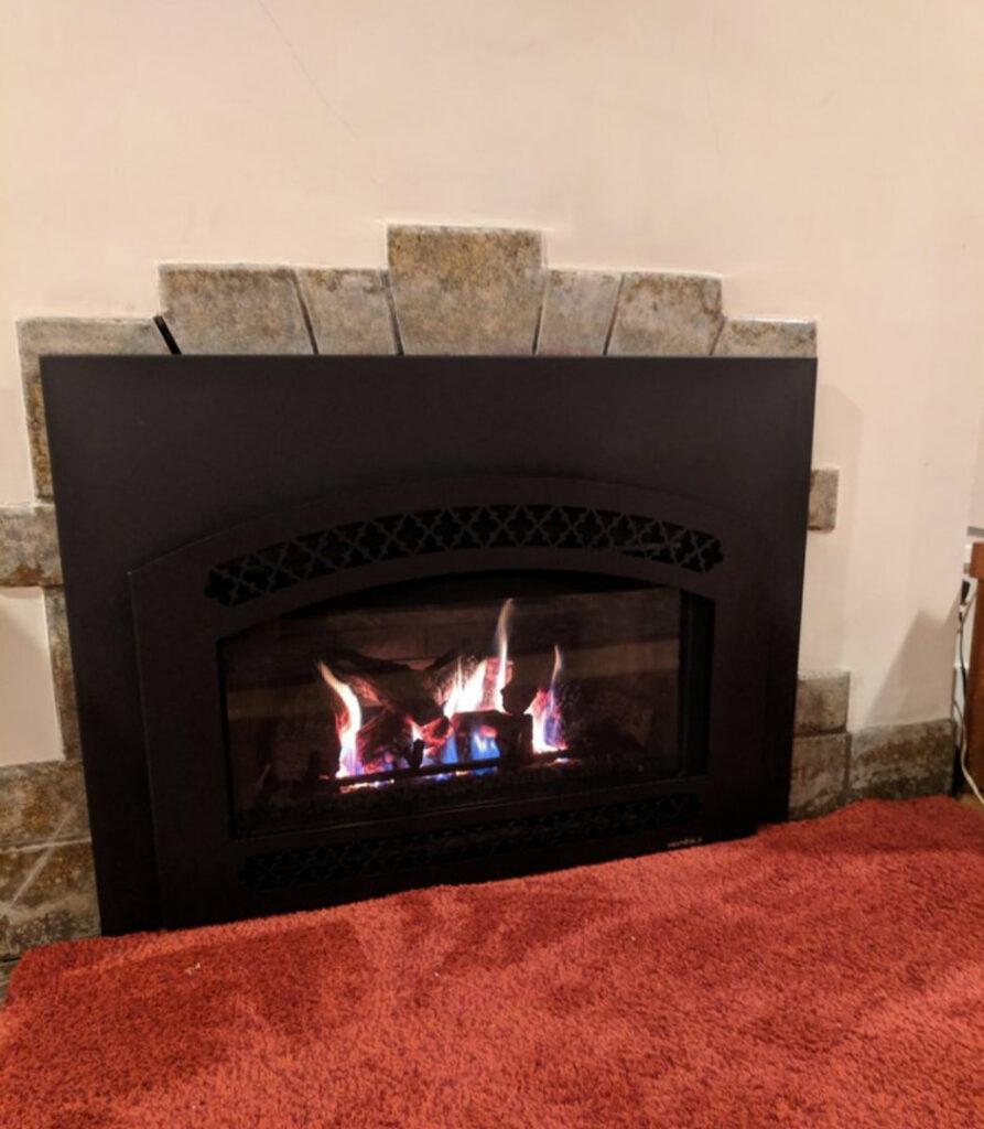 A decorative gas fireplace with a black front and active flames, showcasing a heating solution by Precision Energy LLC in Everett, WA.