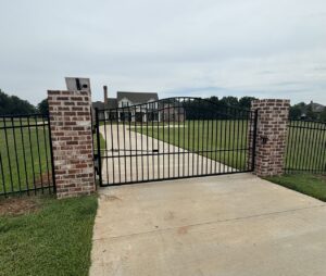 A decorative metal gate with brick pillars at a residential driveway entrance, installed by Lynch's Temporary Fencing & Dumpster rental in Bossier City, LA.