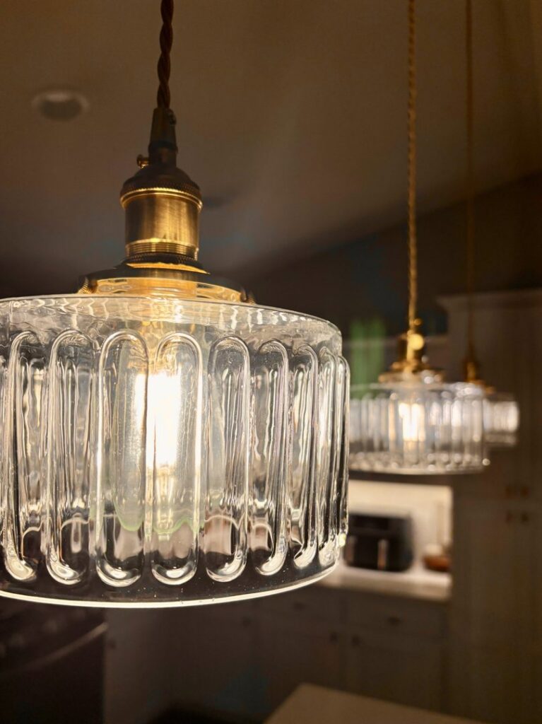 Close-up of two decorative glass pendant lights professionally installed by Woodford Power & Light Co. in Ankeny, IA.