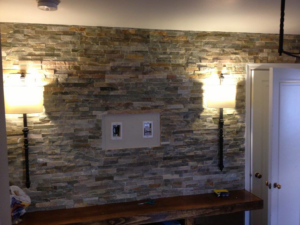 A stone accent wall featuring decorative wall sconces and a media electrical box installed by Arc-n-Spark Electric in Cheyenne, WY.