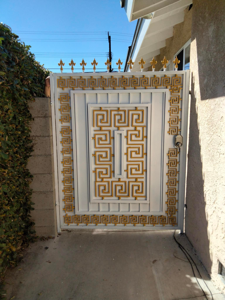 A decorative white and gold metal gate with a unique pattern, installed by Portugal's IronWorks in Los Angeles, CA.