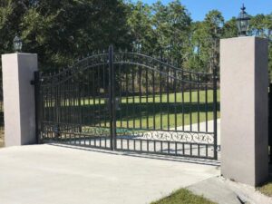 A decorative wrought iron entry gate with sturdy stone pillars, expertly installed by Fencing & Railing 2 Corp in Orlando, FL.