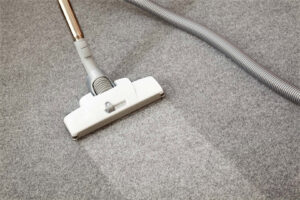 A vacuum cleaner head on a grey carpet, showing a clean path after a deep carpet cleaning service by Carpet Cleaning - American Way in Danbury, CT.