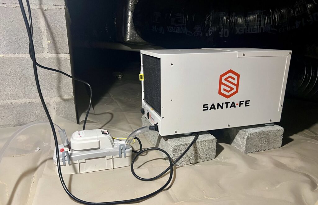A dehumidifier and pump installed on a moisture barrier in a crawl space by Perry Crawl Space & Pest Control Solutions LLC in Chesapeake, VA.