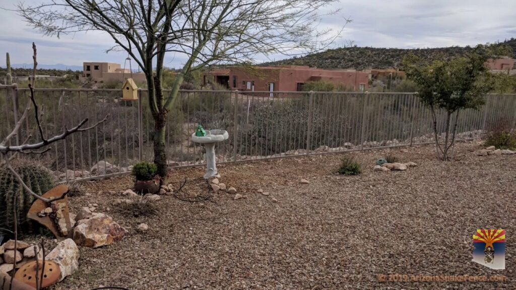 A long metal snake fence with a block base installed in a desert landscape by Arizona Snake Fence LLC in Tucson, AZ