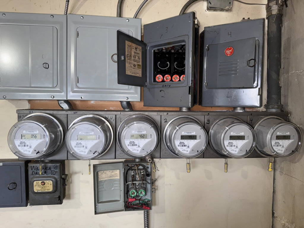 Detailed view of electrical meters and open circuit breaker panels showing wiring by OCD Electric in Spokane, WA.