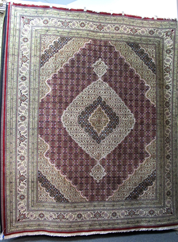 A large oriental rug featuring a prominent diamond pattern in red, cream, and black from Iowa Oriental Rug Co in Davenport, IA.