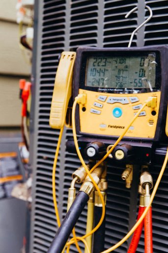 A digital manifold gauge connected to an outdoor AC unit during service by The Right Flow Heating and Air LLC in Lawton, OK