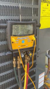 A digital manifold gauge connected to an AC unit, displaying diagnostic readings by Texas Air & Heat in Arlington, TX.