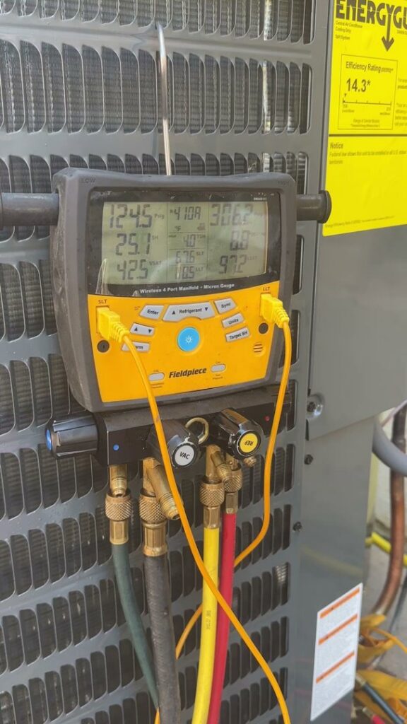 A digital manifold gauge connected to an AC unit, displaying diagnostic readings by Texas Air & Heat in Arlington, TX.