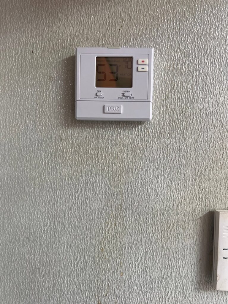 A digital thermostat installed on a wall, showing temperature settings by Spartan Mechanical KC in Spring Hill, KS.
