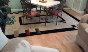 A large patterned area rug placed under a dining table on a hardwood floor by Sunshine Rugs and Art in Londonderry, NH.
