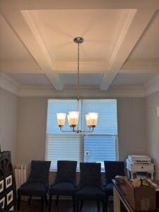 A chandelier installed in a dining room with a coffered ceiling by Onsite Electrical Services in Raleigh, NC.