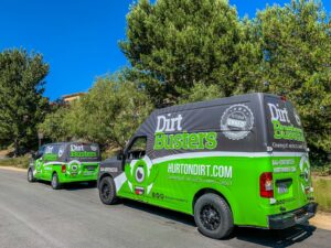 Two Dirt Busters, Inc. service vans parked on a street, clearly advertising carpet cleaning services in Anaheim, CA.