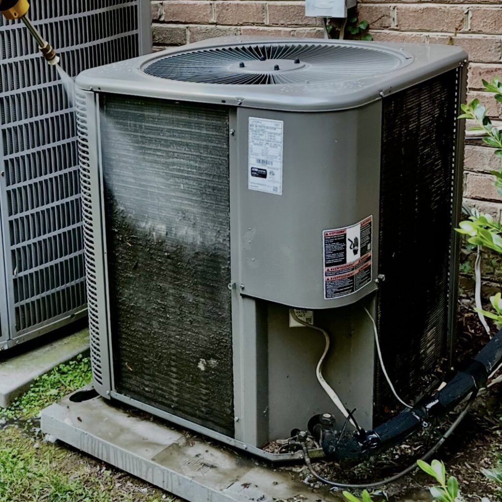 A dirty outdoor AC condenser coil being cleaned during service by Infinite Heating & Air in Newnan, GA.