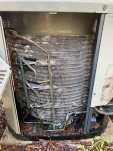Close-up of dirty and potentially corroded coils inside an outdoor AC unit, requiring service from Fix It Now Heating and Cooling in Thornton, CO