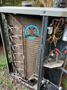 Very dirty condenser coils inside an outdoor AC unit, indicating a need for cleaning by 2 Brothers HVAC in Seguin, TX
