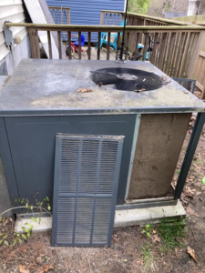A dirty outdoor AC unit with its side panel removed, ready for cleaning or repair by Your Angel Heating And Cooling LLC in Cary, NC.