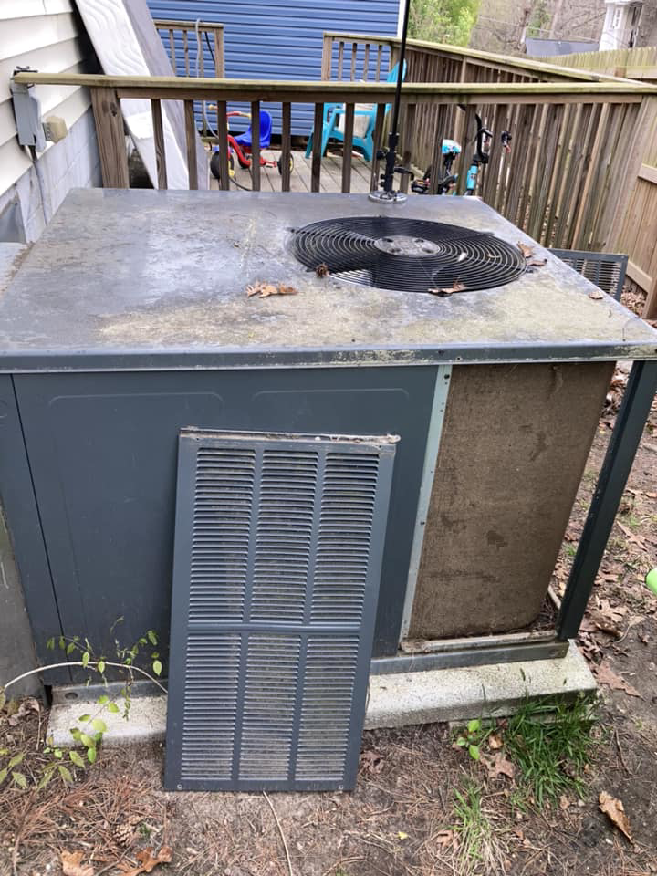 A dirty outdoor AC unit with its side panel removed, ready for cleaning or repair by Your Angel Heating And Cooling LLC in Cary, NC.