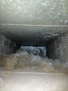 A heavily clogged and dirty air duct before cleaning by Richmond Restoration in Worcester, MA