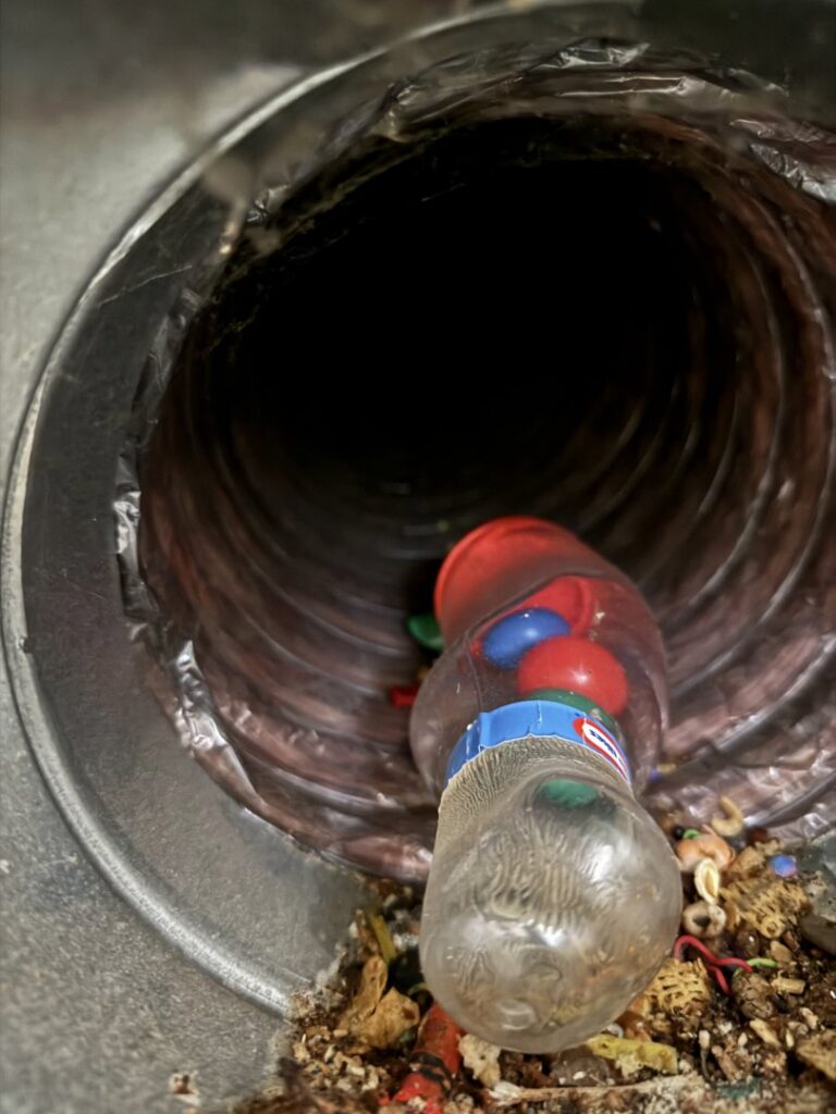 A dirty air duct interior filled with debris and a plastic bottle, requiring cleaning by Boston Air Ducts Cleaning in Newton, MA.