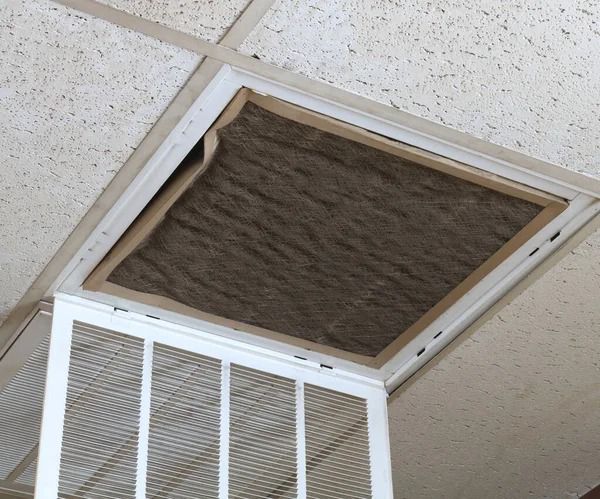 A dirty air filter being replaced in a ceiling vent, a service provided by Murray's General Services in Goose Creek, SC.