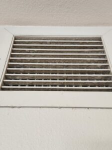 Close-up of a dirty air return vent grille covered in dust, showing a common issue addressed by DUCTZ of Siouxland in Vermillion, SD.
